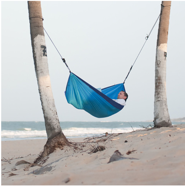 A man sleeping in a parachute material hammock.