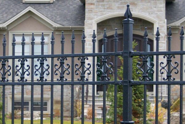 An Nuvo Iron fence surrounds a large stone home.
