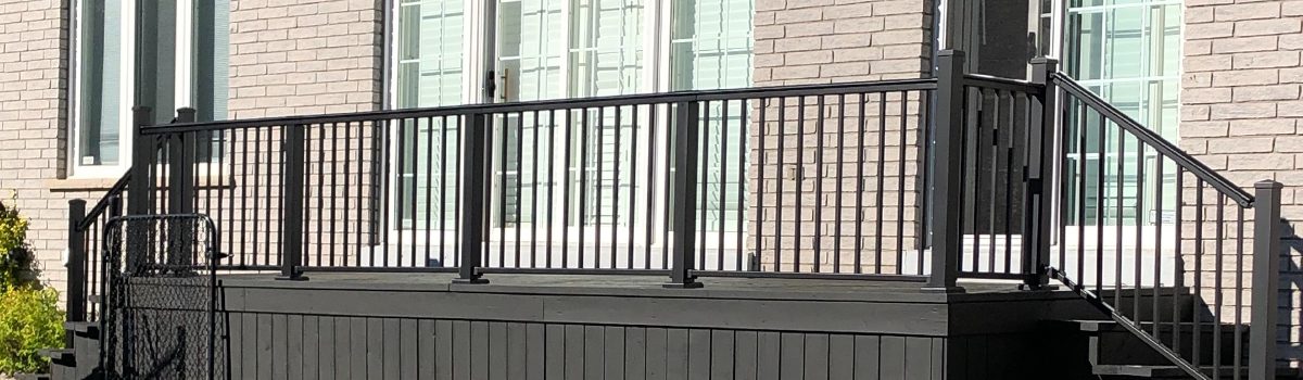 A deck with black railings and two sets of stairs.