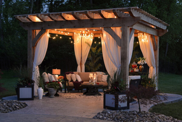A pergola with string lights and lavish furniture and decor.