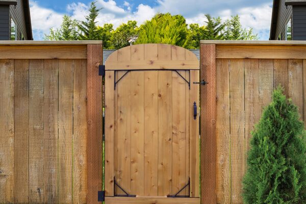 Wood gate reinforced with black corner braces at the top and bottom corners to prevent sagging