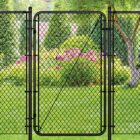 Black chain link gate installed in a lush backyard setting with a tree, evergreen shrubs, and pink flowering plants in the background.