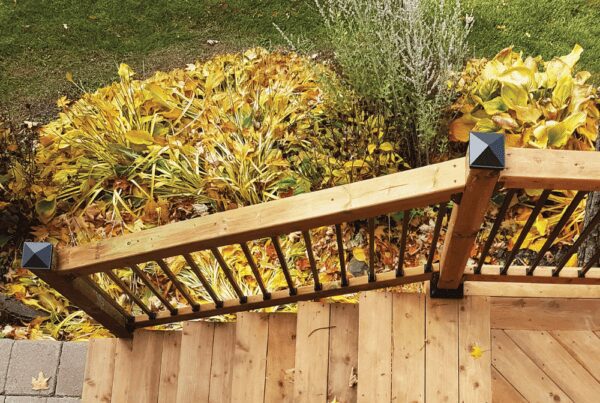 Black pyramid-style Nuvo Iron post cap installed on a wood deck railing post.
