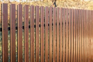 Stunning landscape features weave along the base of chain link fence (Credit: Pinterest).
