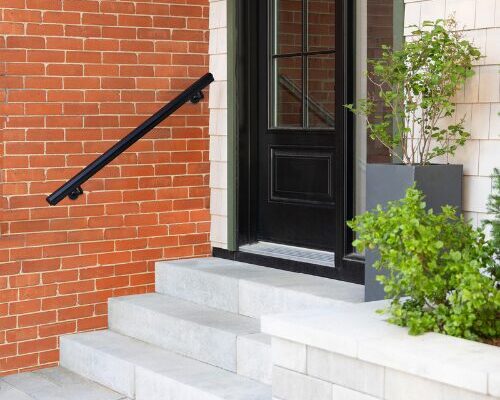 nuvo iron black metal stair handrail deck accessory mounted beside modern front entry steps with brick exterior